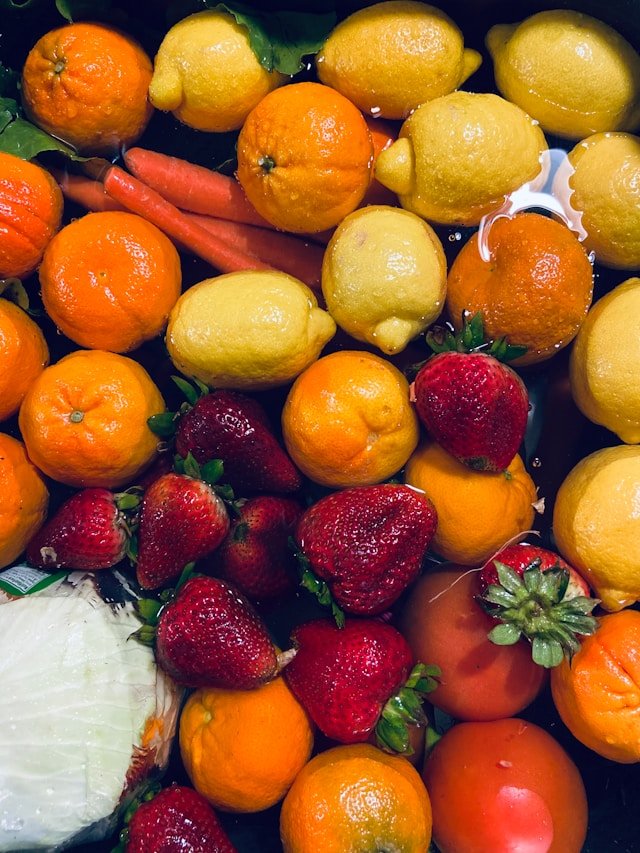 Fresh assorted fruits and vegetables including oranges, lemons, strawberries, and carrots being washed, representing Smart Agnes’s strict quality control and fresh produce import services in Qatar.