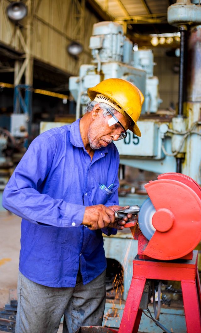 An experienced industrial technician using a bench grinder in a workshop, illustrating Smart Agnes’s commitment to providing highly skilled and site-supervised manpower in Qatar.